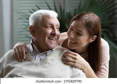 Close up head shot happy young woman and elderly father enjoying tender moment, looking at each other, smiling grownup daughter hugging mature man from back, two generations having fun together