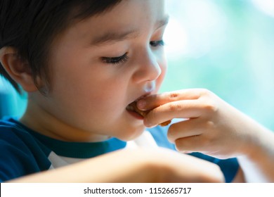 Close Up Head Shot Of Hungry Little Boy Eating Scampi, Selective Focus Of Child Putting Scampi In His Mouth, CLose Up Side View Of Kid Face Enjoy Eating Food With Blurry Bokeh Background