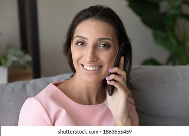 Close Up Head Shot Portrait Of Beautiful Young Indian Arabic Mixed Race Ethnicity Woman Holding Mobile Phone Conversation, Calling Friends Or Family, Discussing Sharing Life News, Looking At Camera.