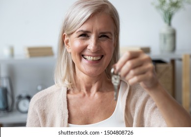 Close Up Head Shot Portrait Happy Older Woman Holding Key From Own Apartment, Looking At Camera, Excited Mature Female Owner Moving Into New House, Satisfied Client Customer Purchase Real Estate