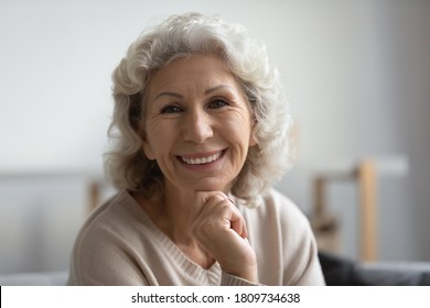 Close Up Head Shot Portrait Happy Beautiful Mature Middle Aged Woman With Healthy Toothy Smile Looking At Camera, Sitting On Cozy Sofa At Home, Posing For Photo, Natural Beauty And Skincare