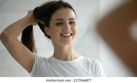 Close Up Head Shot Smiling Young Woman Wearing White T-shirt Holding Long Healthy Strong Brown Hairs, Doing Hairstyle, Happy Satisfied Beautiful Female Standing In Bathroom, Looking In Mirror