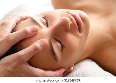 Close up head shot  of Woman having curative facial massage. Therapist applying pressure with thumbs on forehead. - Powered by Shutterstock