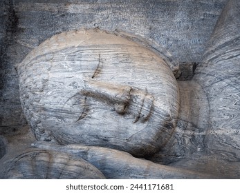 Close up of head from a statue of reclining Buddha hewn out of solid granite in the Gal vihara of Ancient city Polinnaruwa, Sri Lanka. The statue carved out of rock is a master piece of ancient Art.