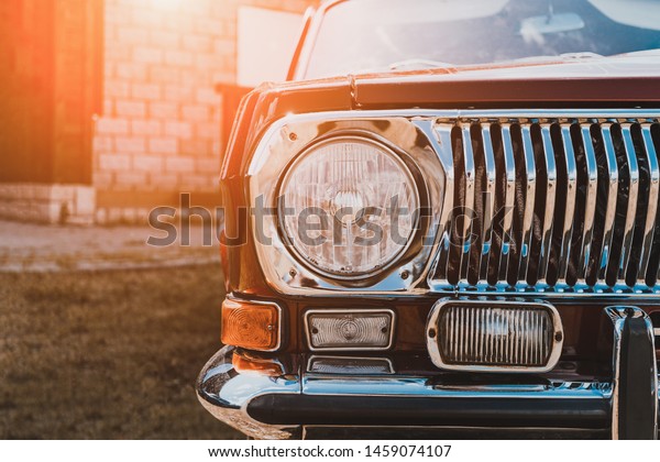 Close up of headlight of custom tuned\
classic retro lowrider car in sunlight,\
toned