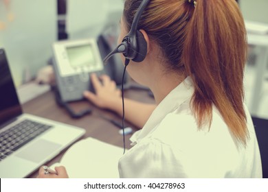 close up headphone asian girl press number on telephone and response answer customer or partner in operation room for business and technology concept.
