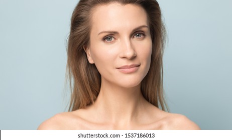 Close Up Headshot Portrait Of Beautiful Young Caucasian Woman With Clean Healthy Skin Isolated On Blue Studio Background Look At Camera, Blonde Millennial Female Posing Show Skincare Treatment Result