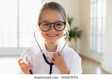 Close Up Headshot Portrait Of Cute Little Caucasian Girl Child In Medical Uniform Stethoscope Play Act Doctor. Profile Picture Of Small Smiling Kid Have Fun Enjoy Hospital Game. Healthcare Concept.