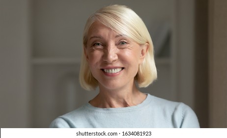 Close up headshot portrait of happy middle-aged woman look at camera feel positive, smiling joyful senior mature female posing at home show white healthy teeth veneers, optimistic lifestyle