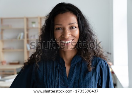 Close up headshot portrait picture of smiling african american businesswoman. Happy attractive confident young diverse woman mentor looking at camera on workplace background in coworking office.