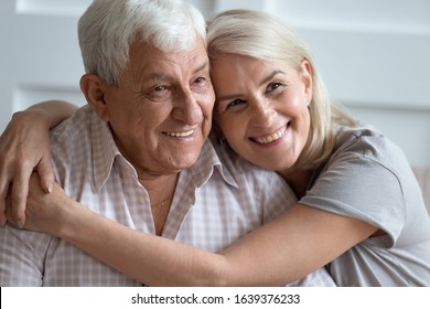 Close up headshot portrait of smiling elderly couple hug cuddle showing love and care, family picture of mature husband and wife embrace enjoy tender sweet moment on home weekend together - Powered by Shutterstock