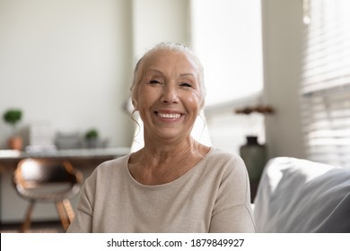 Close up headshot portrait of smiling senior female have webcam virtual digital conversation on computer. Happy modern mature woman speak talk on video call at home. Elderly and technology concept.