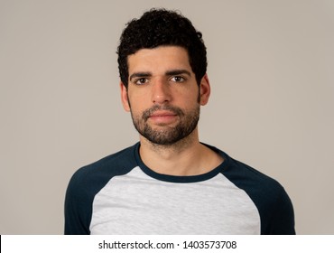 Close up headshot of young latin man with natural and neutral face expression with beard and dark hair. Isolated on neutral background. In People fashion, Lifestyle Beauty and Human emotions.