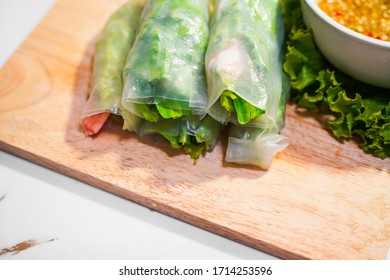 Close up healthy fresh green vegetable salad roll with red shrimp and spicy sauce  on the wooden board on white marble background - Shutterstock ID 1714253596