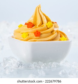 Close Up Healthy Frozen Yogurt With Little Toppings On White Bowl Surrounded By Ice Pieces On Sides. Isolated On White Background.