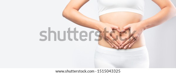 Close up healthy Stomach Ache\
woman hands made heart on belly isolated on white background banner\
size. gut health care digestion concept. \
Stomach health woman\
.