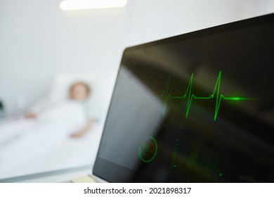 Close Up Of Heart Monitor Display In Hospital With Child Laying In Bed In Background, Copy Space