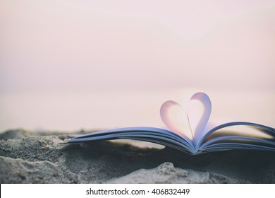 Close up heart shape from paper book on sand in the beach with vintage filter blur background