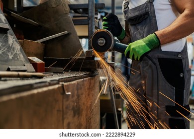 Close up of heavy industry worker using grinder to cut metal parts.