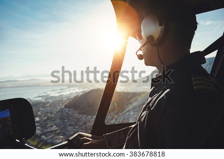 Close up of a helicopter pilot flying aircraft over a city on a sunny day