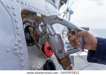 close up of the helicopter refueling  operation onboard the navy ship while the ship is underway at sea