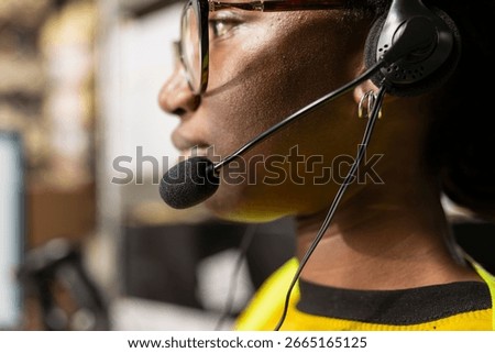 Close up of help line worker responding to issues like lost parcels or order tracking, surrounded by cargo boxes on storage racks in a fulfillment center. Call center retail activity on headset.