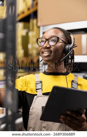Close up of help line worker responding to issues like parcels delays or wrong address for orders, working in warehouse with huge racks. Black woman uses headset for call center.