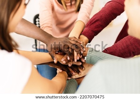 Close up high angle view of diverse young people putting their hands together - Support, unity and teamwork concept with multiracial group of teenager friends stacking hands sitting in circle