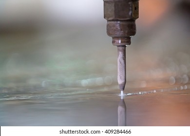 Close Up High Pressure Water Jet Stream Exits The Nozzle As A Three Phase Mixture Of Air, Water And Abrasive Particles During Granite Or Marble Tiles CNC Cutting In Factory Workshop