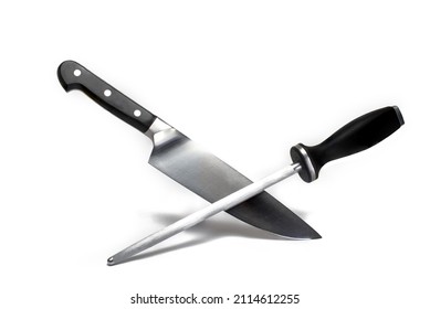 Close up of a high quality large sharp meat kitchen knife crossed with a long grinding stick both with black handle on white background concept for knife sharpening and sharp knives