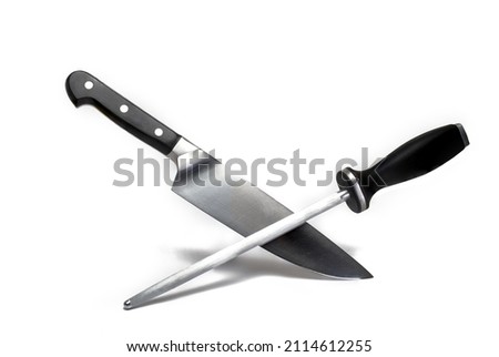 Close up of a high quality large sharp meat kitchen knife crossed with a long grinding stick both with black handle on white background concept for knife sharpening and sharp knives