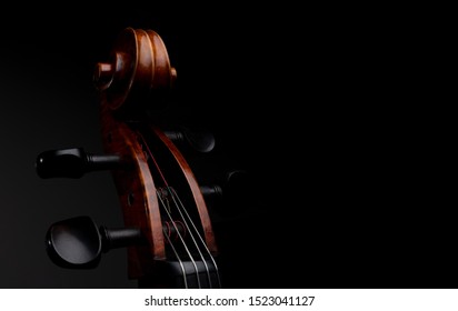A close up high resolution image of a cello scroll, peg box, and tuning pegs isolated against a black background