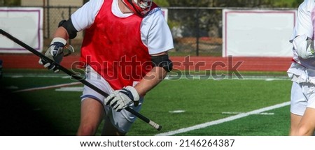 A close up of a high school boy lacrosse player running with the ball during a scrimmage on the attack.