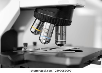 Close up of a high-precision laboratory microscope with 10x, 40x, and 100x objective lenses, used for scientific research, medical diagnostics, biotechnology, and microbiology analysis in a profession