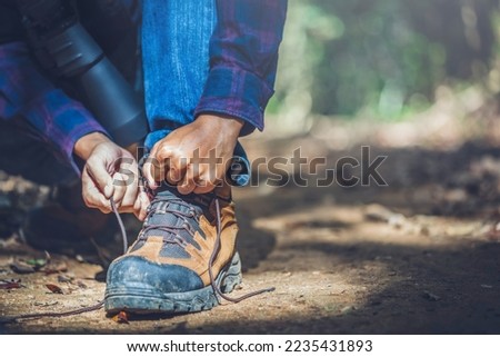 Close up hiker boots and hands tying bootlaces in forest