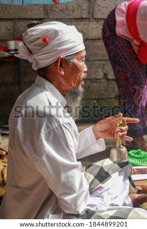 Close up of a Hindu pedanda during prayer. Side view of a sitting priest. Priest holds a bell in his hand and performs the ceremony. Wedding blessing the ceremony.