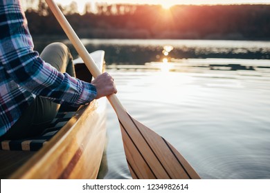 Close up of hipster girl holding canoe paddle. Canoeing on the sunset lake