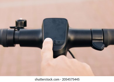 Close up of hipster man turns on the electric scooter. Male is pushing start button of modern gadget and driving along street of city. Hands of a young man close-up. Ecological alternative transport - Powered by Shutterstock