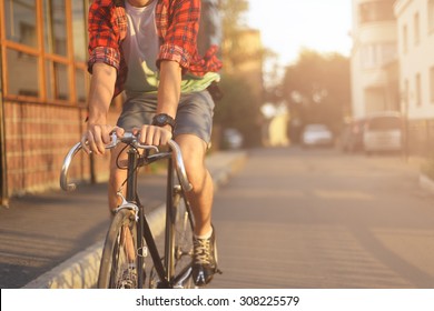 Close up hipster on bike in the city at sunset. Shot with sunflare and without face.