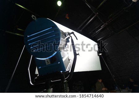 Close up of HMI light on a tripod that illuminating the rectangular reflector frame on the stand set up for shooting photos or tv commercial or video production in the studio.