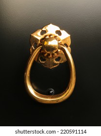 Close Up Home Decorated, Isolated Shiny Classic Gold Ring Pull Handle And Knocker On Black Door Panel