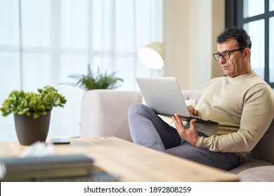 Close to home. Handsome latin middle aged businessman in eyeglasses using laptop while working from home - Powered by Shutterstock