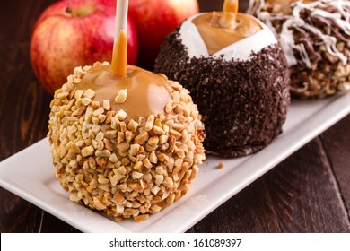 Close Up Of Homemade Caramel Apple Decorated With Peanuts On Rectangular White Plate