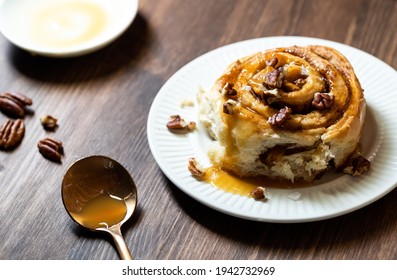 Close Up Of A Homemade Cinnamon Swirl Topped With Caramel Sauce And Pecan Pieces Taken From Above.