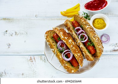 Close up of homemade hot-dogs on ceramic plate with onion, spices and mustard over white painted background, selective focus - Powered by Shutterstock