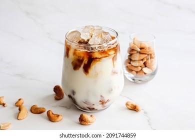 Close up homemade iced latte with plant base milk cashew nut milk with cashew nuts decorated on light background. Self care Healthy eating concept. Copy space. - Shutterstock ID 2091744859