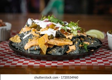 Close Up Homemade Nacho Platter With Guacamole, Jalapeños, And Sour Cream