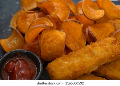 Close Up Homemade Organic Baked Fried Sweet Potatoes Chips And Fish Fingers Served Home Made Tomato Sauce On Black Slate Plate, Healthy Snack For Family Concept