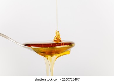 Close Up Of Honey Being Poured Into A Silver Spoon, Honey Is A Natural Sweetener As A Substitute For Sugar