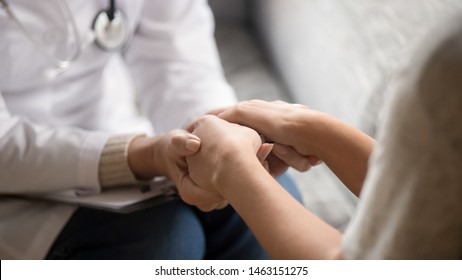 Close up horizontal image doctor in white uniform holding hands of female patient, showing support, gave professional aid psychological help, disease express of empathy and trusted specialist concept